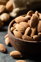 Wall Mural - Delicious sweet almonds in wooden bowl or burlap sack on rustic background, roasted almond nut, healthy food