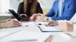 © H_Ko - Group of business people are sitting at table with laptop and documents with charts closeup. New modern approaches to development of small and medium-sized businesses concept