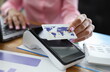 © H_Ko - Close-up of adult person holding plastic credit card and machine on table. Business office and executive manager. Statistics report. Online shopping and remote transaction concept