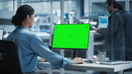 Leinwandbilder - Hispanic Female Robotics Engineer Using Desktop Computer with Green Screen Chromakey Mock Up Display in Factory Office. Technological Research and Development Facility with Autonomous Assembly Line.
