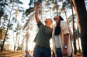 Man showing something to the woman. Group of friends are together in the forest