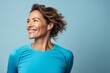 © Markus Schröder - Portrait of a happy woman in her 40s sporting a breathable mesh jersey against a soft blue background. AI Generation