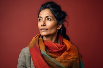 Wall Mural - Portrait of a tender indian woman in her 40s wearing a cozy sweater against a soft multicolor background. AI Generation