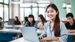 © Cassova - A student smiles at the camera while working on a laptop in a classroom
