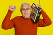 © Andrii Iemelianenko - Senior old man using retro tape record player to listen music, disco dancing favorite track, having fun, entertaining, fan of vintage technologies. Mature grandfather pensioner on yellow background