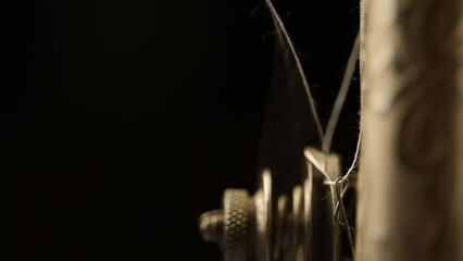 Wall Mural - The metal part of the sewing machine in work with white threads on a dark background