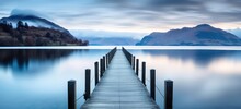Tranquil Lake Pier Leading Into Misty Mountains At Dawn. Serenity And Nature.