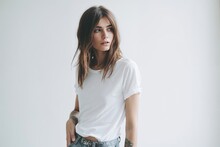 Jeune Femme En T-shirt Blanc Et Jeans Contre Un Mur Blanc