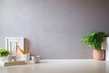 Creative designer workplace with picture frame mock up stationery and potted plant on white table.