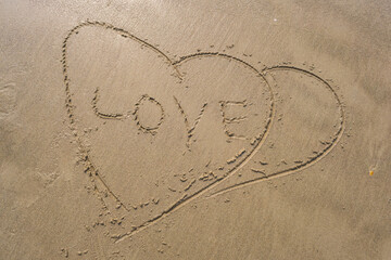 drawing in sand in form of two hearts and inscription love