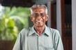 Portrait of a smiling indian man in his 70s dressed in a casual t-shirt against a stylized simple home office background. AI Generation
