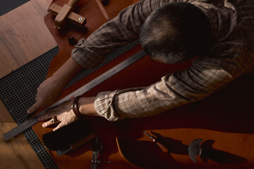 Wall Mural - cutting leather belt process, top view, cropped photo.man cutting lines, stipes with a knife at workshop.