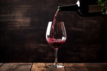 Poring Red Wine In A Glass On Dark Background. Red Wine Is Poured Into A Glass From A Bottle