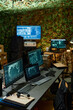 © Seventyfour - Desk with group of computer monitors with graphic data on screens standing in front of camera in spacious military office