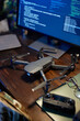 © Seventyfour - Grey military drone standing on desk with computer monitor, remote control, eyeglasses and folder with important secret documents