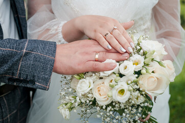 Wall Mural - Hands of the bride and groom on a wedding bouquet