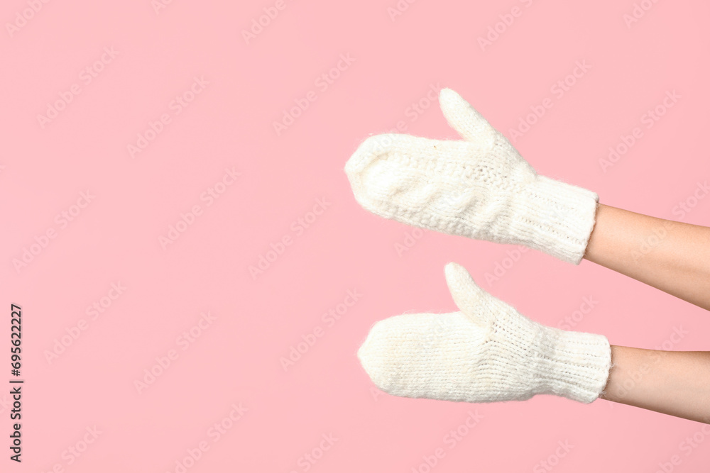 Hands in warm mittens on pink background