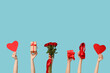Female hands with bouquet of roses, paper hearts and gift boxes on blue background. Valentine's Day celebration