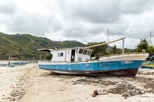 Abandoned Blue And White Fishing Boat Rests On Sandy Beach Under A Clouded Sky, Indonesia, Asia