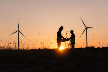 Silhouette of Engineer in charge of wind energy against a background of wind turbines.