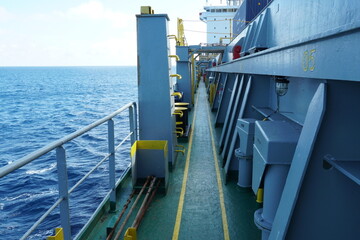 Wall Mural - Main deck of container vessel painted green viewed from forward part of the ship. In the aft is white superstructure and on the side grey hatch coamings and railings.