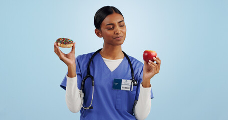 Apple, donut and nurse in studio with choice for healthy eating, diet and detox on blue background. Thinking, healthcare and Indian woman with dessert, fruit and cake for decision, option and balance