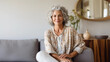 © Dirk - copy space, stockphoto, middle aged woman sitting on sofa at home, single mature senior in living room. Happy woman sitting. Carefree lifestyle. Aged woman in good health.