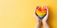 Two Hands Forming A Heart Shape In Front Of A Vibrant Rainbow Flag. This Image Symbolizes Love And Support For The LGBT