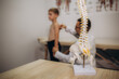 A pediatric neurologist doctor examines the back of a 5-year-old boy who has back pain. Treatment of muscle pain and scoliosis in children
