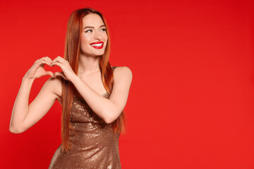 Wall Mural - Young woman in dress making heart with hands on red background, space for text