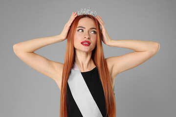 Poster - Beautiful young woman with tiara and ribbon in dress on light grey background. Beauty contest