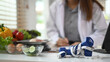 © Prathankarnpap - Measuring tape, dumbbells and vegetables on table at diet clinic. Weight loss and healthy eating concept