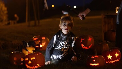 Sticker - Two boys in the park with Halloween costumes, carved pumpkins with candles and decoration, playing