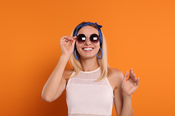 Canvas Print - Portrait of smiling hippie woman in sunglasses on orange background