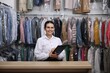 © New Africa - Dry-cleaning service. Happy worker with clipboard at counter indoors