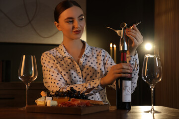 Canvas Print - Romantic dinner. Woman opening wine bottle with corkscrew at table indoors