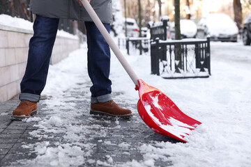 Wall Mural - Man shoveling snow on city street, closeup