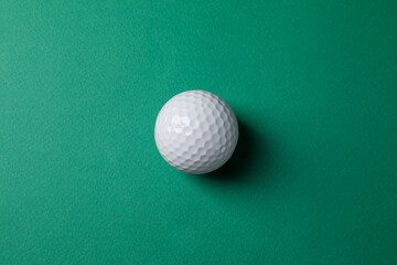 Poster - One golf ball on green background, top view