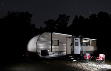 Wall Mural - Forest silhouetted by stars with camping trailer