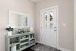 © Joseph Hendrickson - A cozy entryway with brown walls, a green console table with decorations, and a white front door.