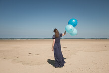 Woman On The Beach In Blue Dress Holding Bunch Of Balloons
