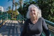 © Leonid - Portrait of a smiling gray-haired lady on a pedestrian bridge.Copy space.