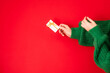 Christmas shopping concept. Flat lie hands in a green sweater with bonus card. Banner on a red background