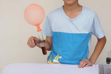 Closeup boy hold test tube with balloon. Science experiment. The expanding of air pressure , reaction of chemical substance. Concept, Science camp activity. Learning by doing.            