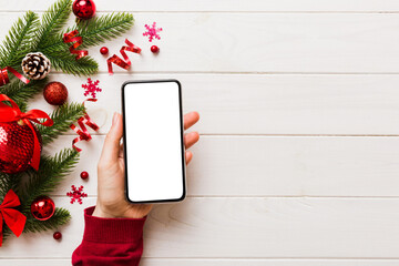 Wall Mural - christmas mockup with space for text. christmas advertising, app template. hand holding phone with empty screen on table background. Happy New Year and Xmas Flat lay