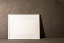 White Frame Leaning On Dark Plaster Wall
