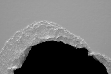 Wall Mural - edge of a torn white sheet of paper on a black background, black hole