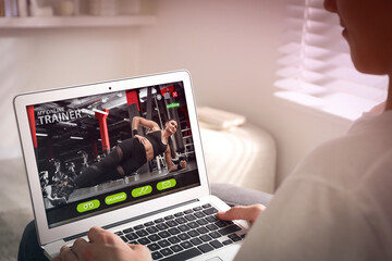 Poster - Personal trainer online. Man viewing website via laptop at home, closeup