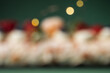 Meringue roll sprinkled with powdered sugar decorated with blueberries, pomegranate and almond flakes on the dark green background with blurred Christmas tree. Christmas festive pastry