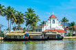 Old colonial Saint Thomas catholic church on the coast of Pamba river, with palms and anchored houseboats, Alleppey, Kerala, South India